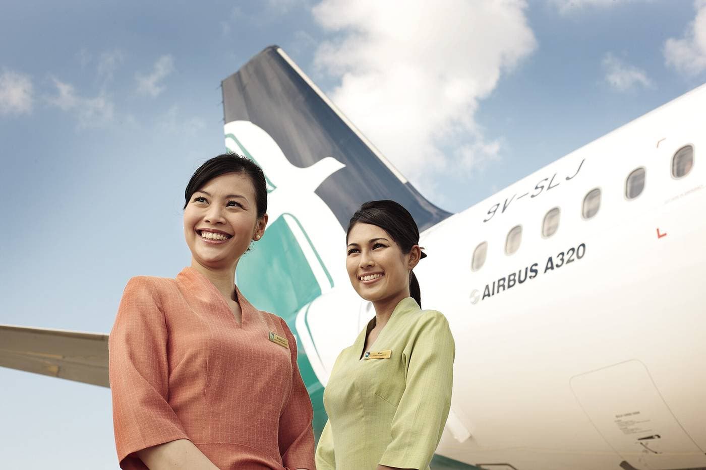 Deux hôtesses de l'air souriantes devant un Airbus A320