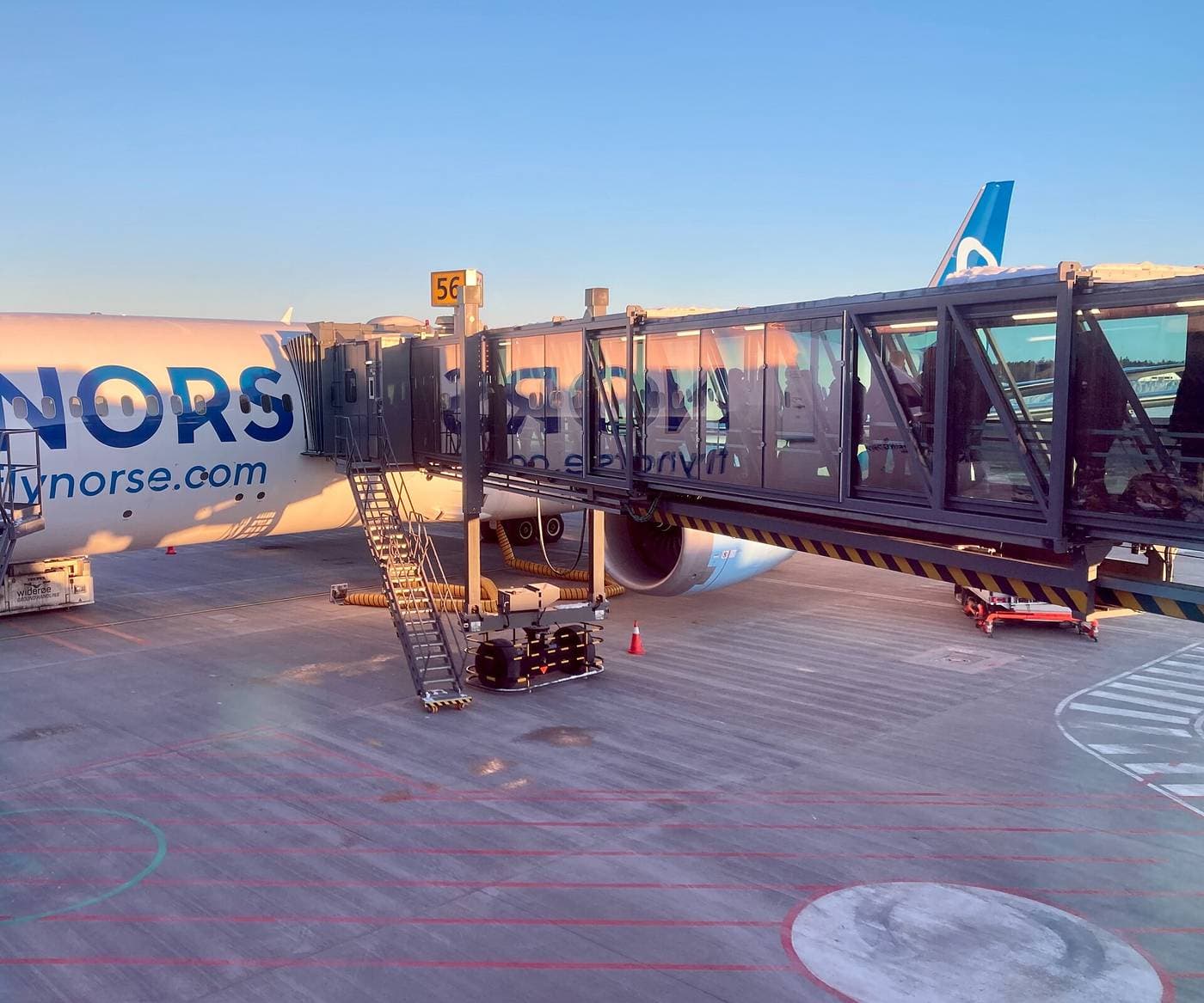 Passerelle d'embarquement reliée à un avion sur le tarmac, au coucher du soleil